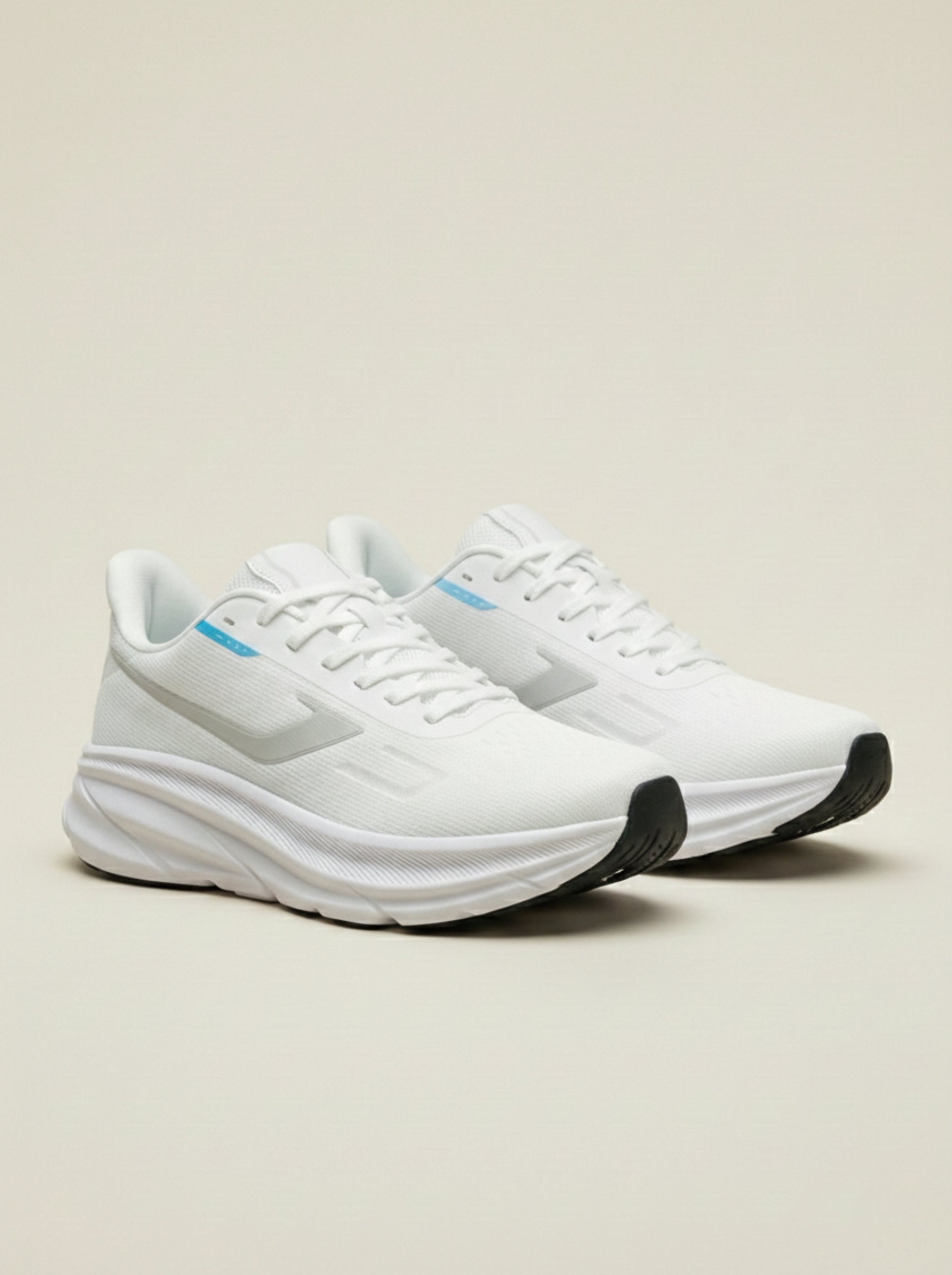 White running shoes with black soles on a light beige background