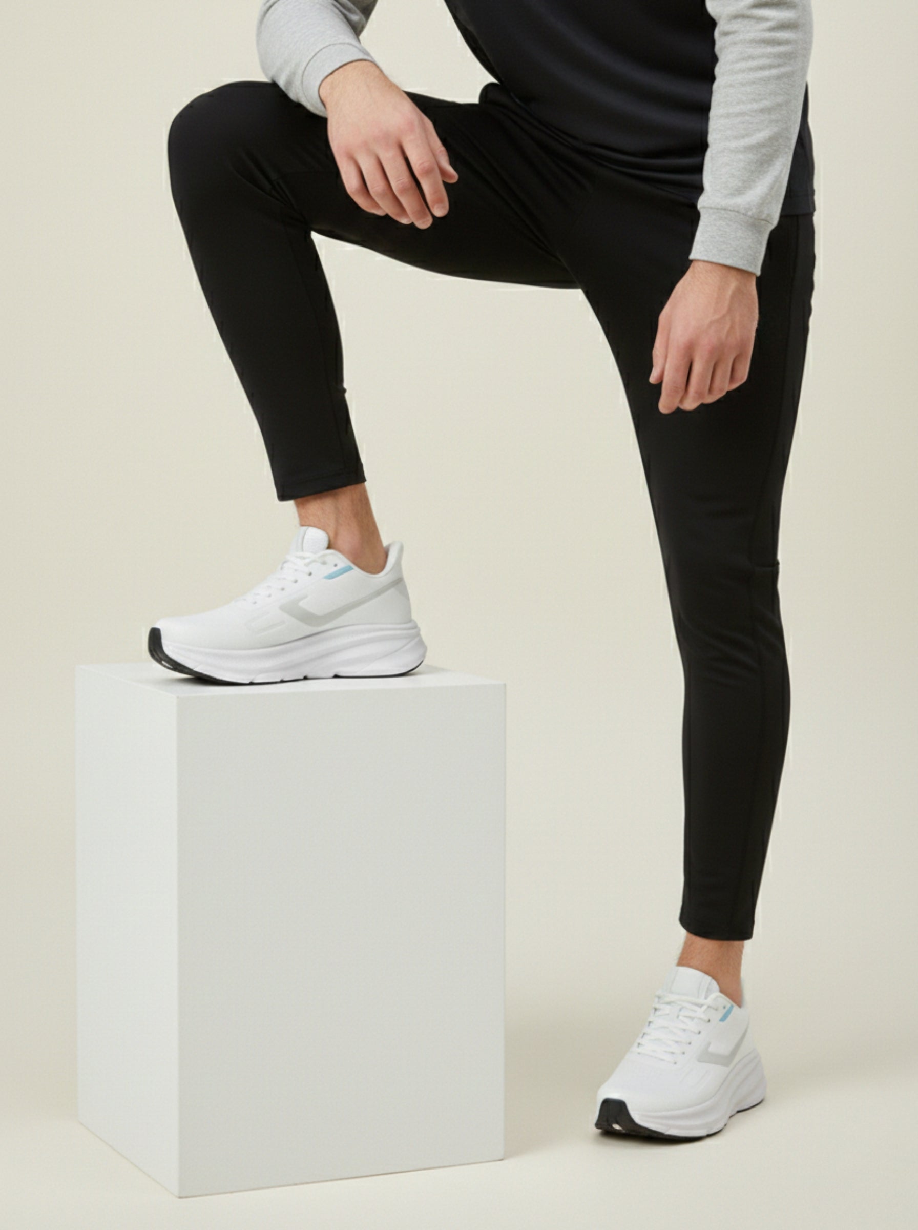 Person wearing black leggings and white sneakers on a beige background