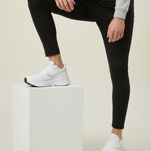 Person wearing black leggings and white sneakers on a beige background