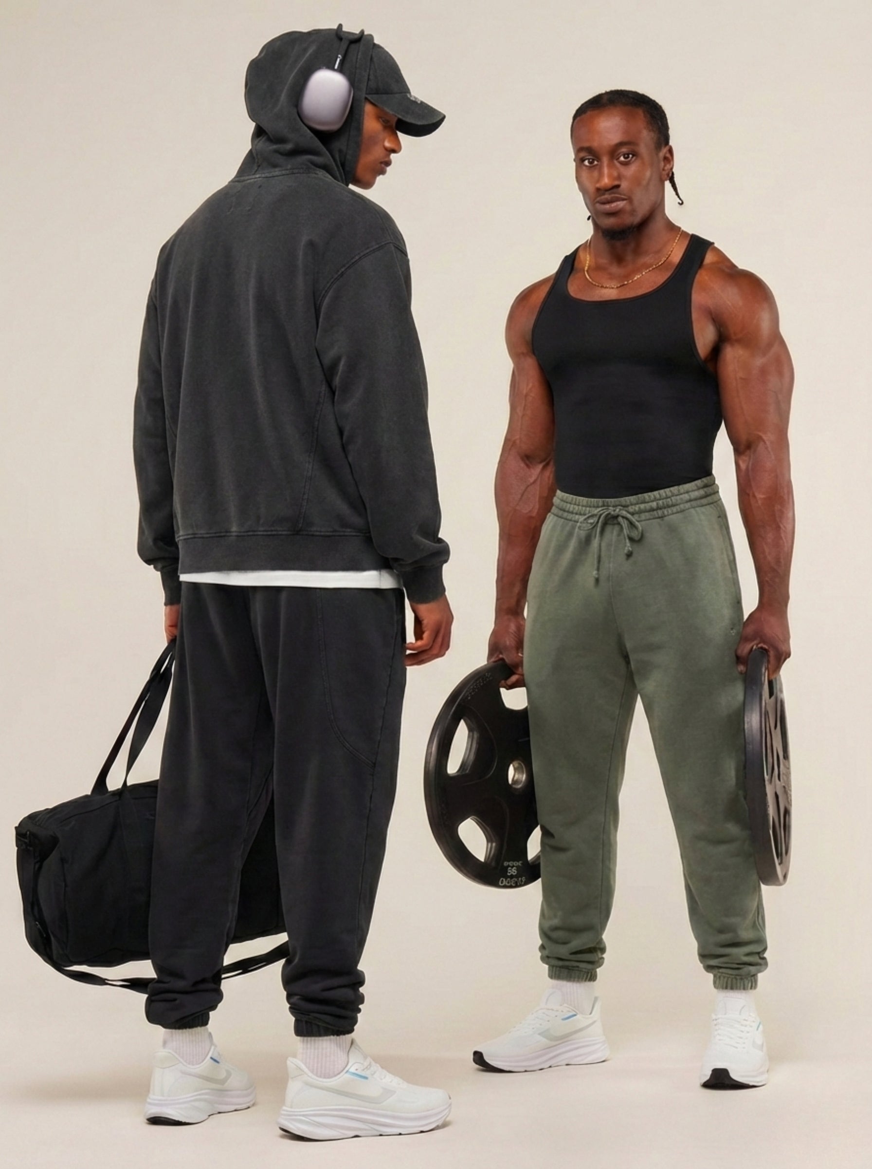 Two men in athletic wear standing next to each other with gym equipment.